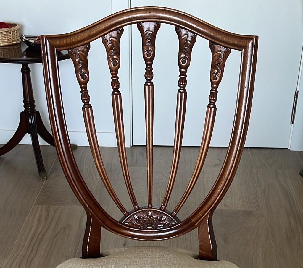 An antique chair feature a padded cushion and some wood-carved details.