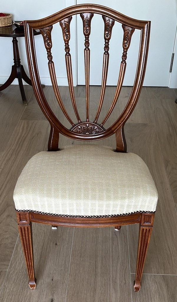 An antique chair feature a padded cushion and some wood-carved details.